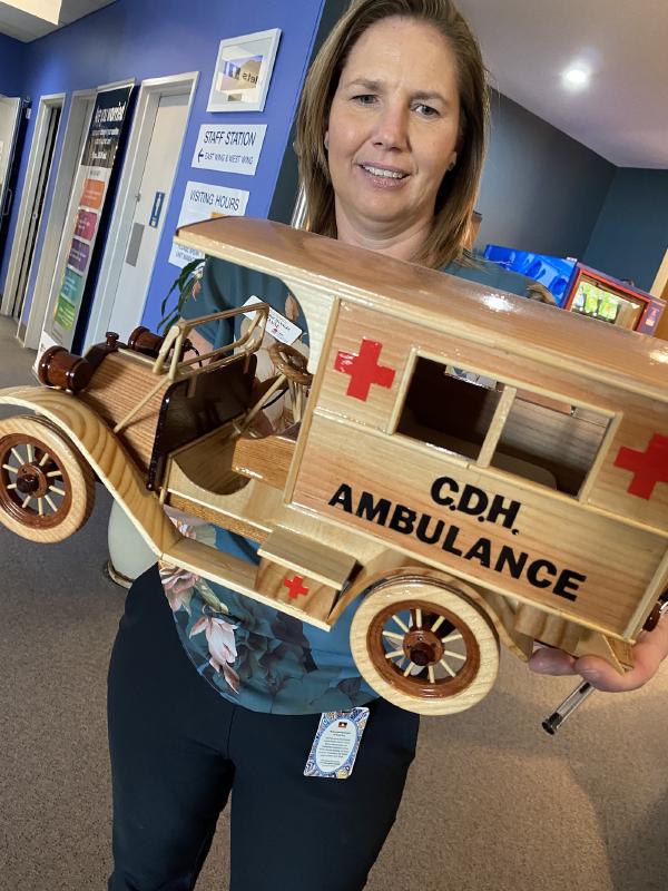 Suzanne Lide holding Ray's handmade gift: a wooden ambulance